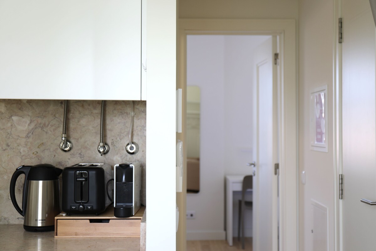 Una cocina con cafetera, tostadora y hervidor sobre la encimera.