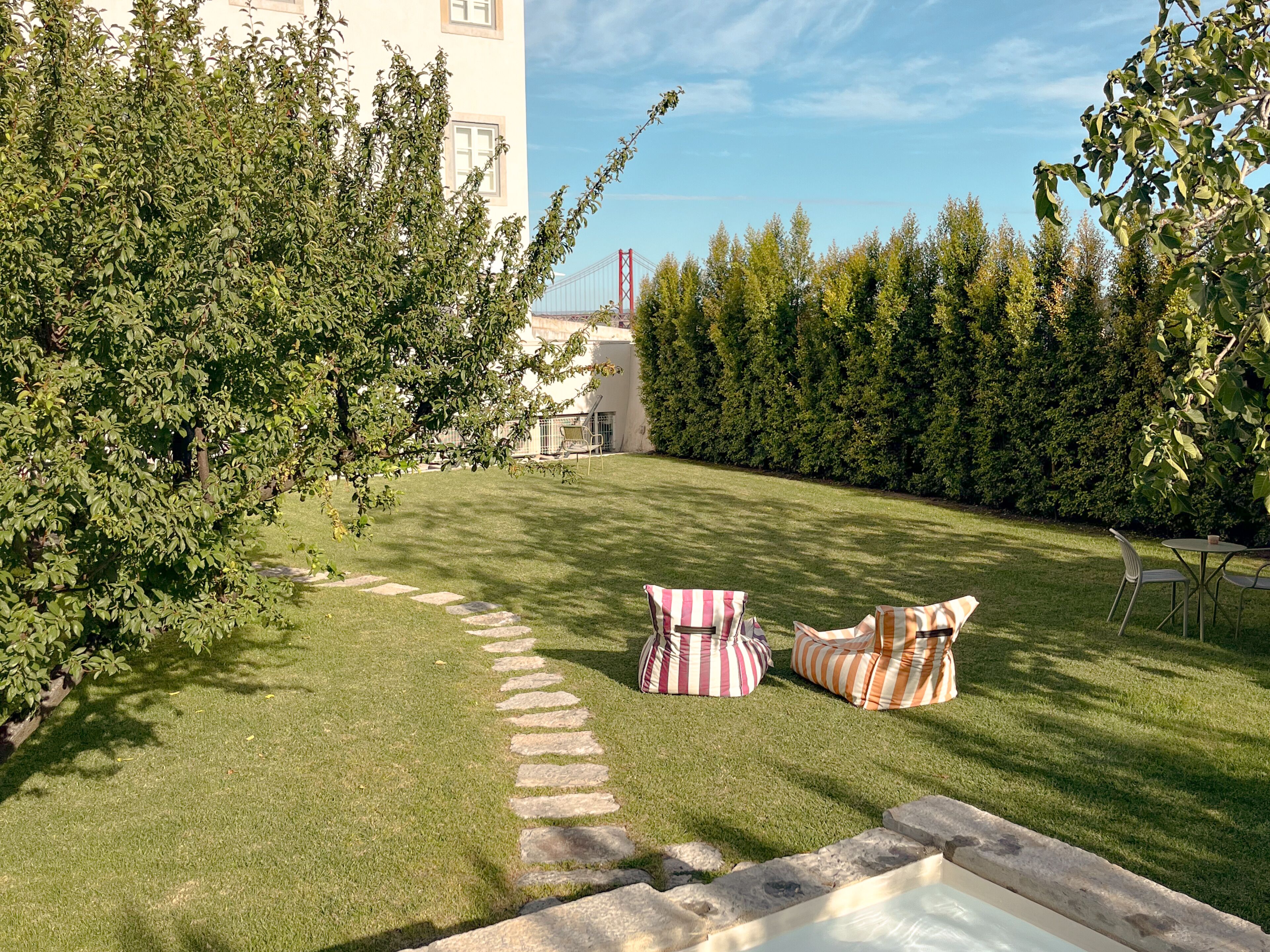 A well-maintained grassy area with stone steps leading to a seating area with striped cushions.