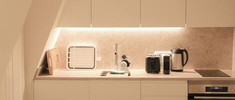 A compact kitchen with a built-in oven, a coffee maker, and a toaster.
