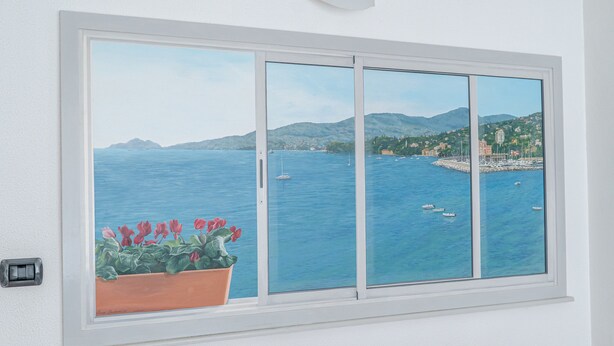 A window with a painting of a coastal scene, including boats and buildings.