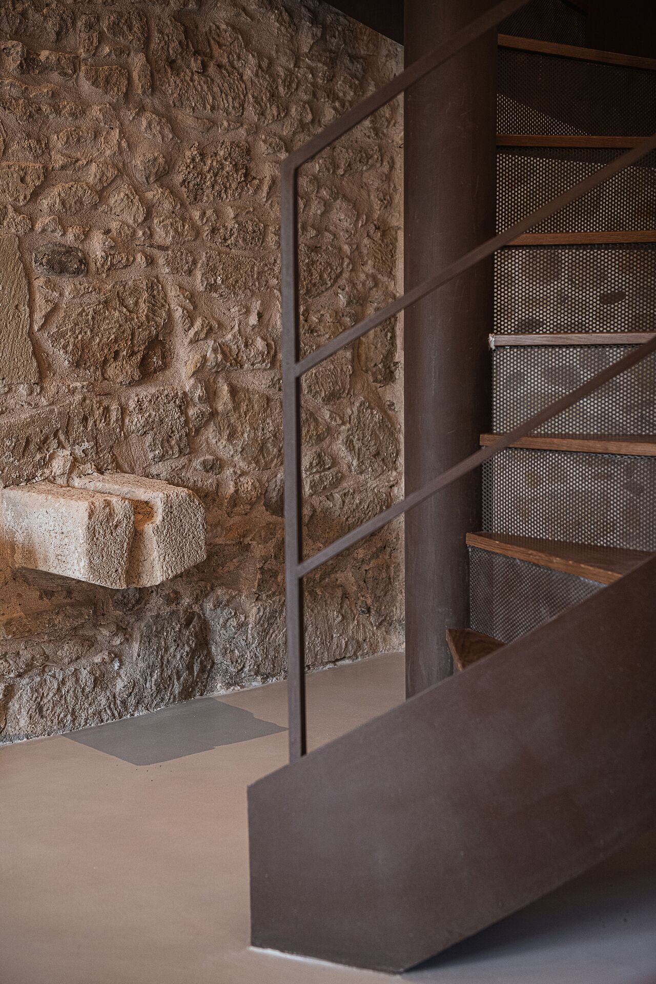 Una escalera con un fondo de pared de piedra y barandilla de metal.