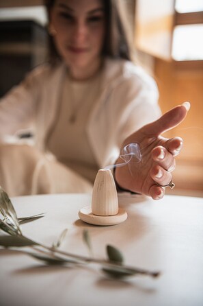 Een hand die een houten voorwerp vasthoudt, met een klein plantje ernaast.