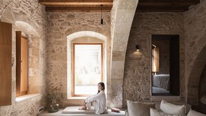 Een kamer met stenen muren, een houten deur, een comfortabele bank en een zachte sofa.