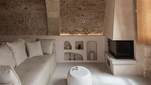 Een rustiek interieur met zichtbare stenen muren, een houten plafond en een ingebouwde open haard.