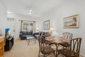 A living room with a sofa, coffee table, and dining table set for four.