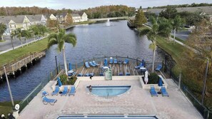A swimming pool with lounge chairs, a no diving sign, and a bridge over a water body. - Renovated 4BR Near Disney | Pools, Jacuzzi & Gym (Kissimmee)