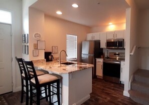 A kitchen with a central island, a refrigerator, microwave, and stove. - Renovated 4BR Near Disney | Pools, Jacuzzi & Gym (Kissimmee)