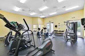 A gym with cardio machines, weightlifting equipment, and dumbbells.