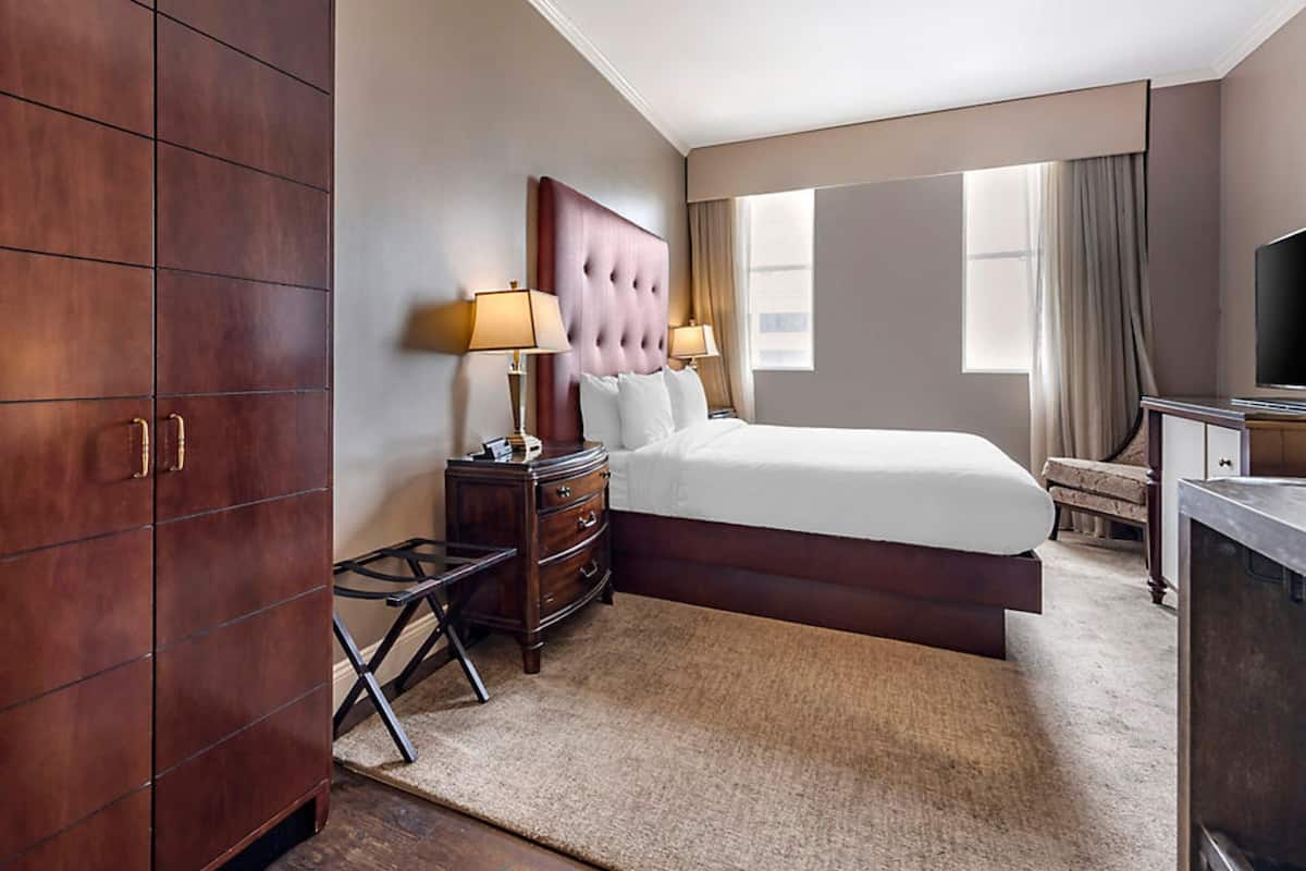 A hotel room with a large bed, two bedside tables with lamps, a wardrobe, and a television.