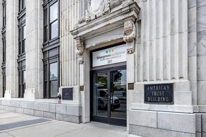 El exterior del American Trust Building, con un estilo arquitectónico clásico, detalles en piedra labrada y una entrada destacada.