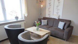 Un salon comprenant un canapé, deux fauteuils, une table basse et un vase avec des fleurs.