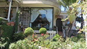 A building with a curved facade, a covered porch with potted plants, and a sign indicating a cafe. - New Listing Ocean View Studio (Honolulu)
