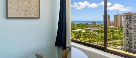 A room with a large window offering a view of a cityscape and a beach.