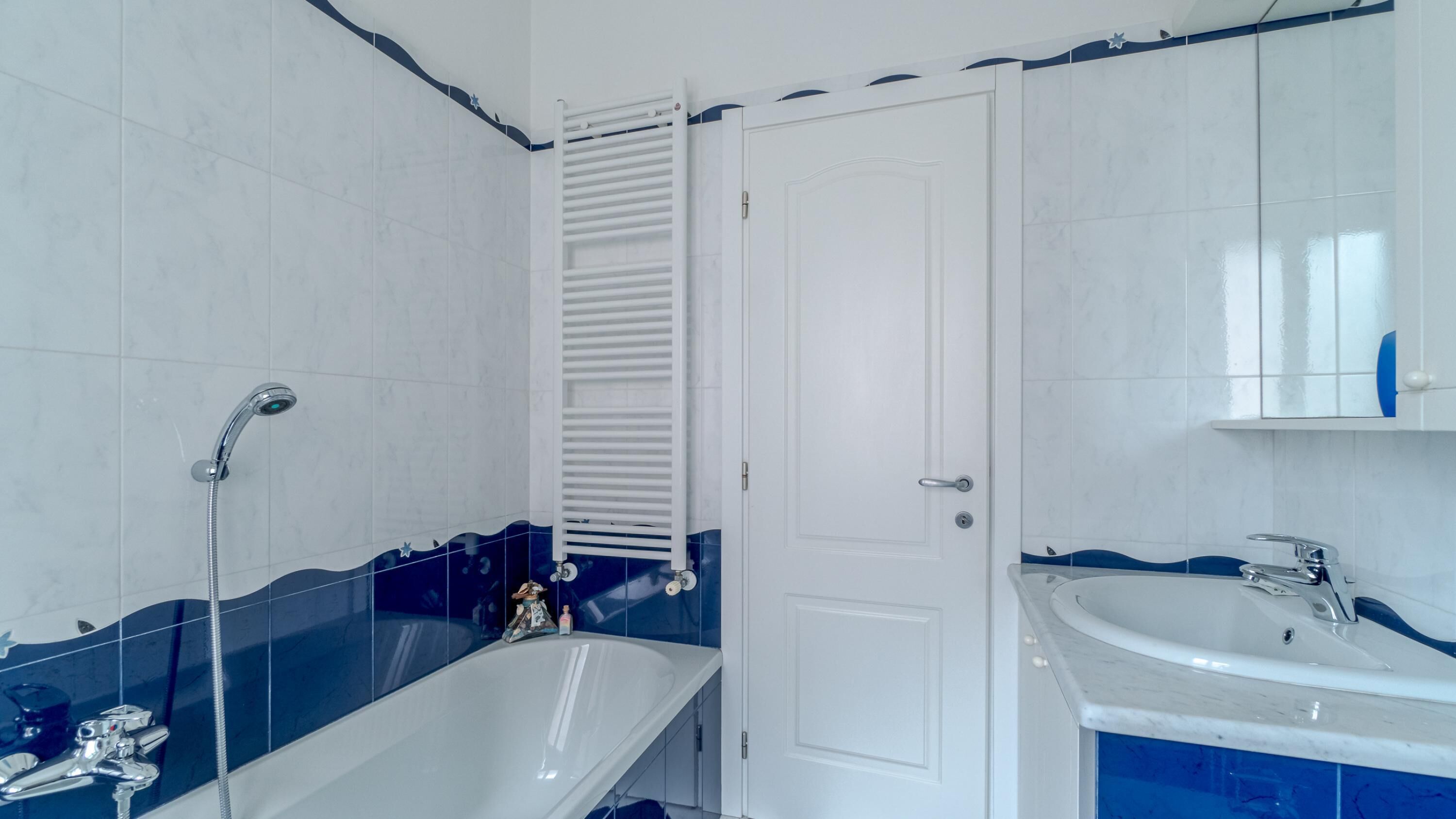 Un baño con una bañera blanca, un lavamanos blanco y una puerta blanca.
