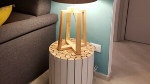 Ett modernt rum med en grå soffa, en unik trälampskärm med en vit fot, turkosa väggar och ett trägolv.