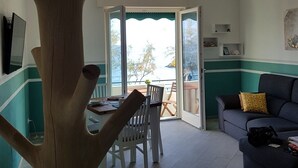 Ett vardagsrum med en stor träskulptur i form av ett träd, en takfläkt, en matplats med ett bord och stolar samt en soffa med en kudde.