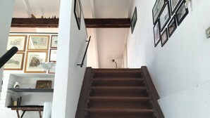 Una escalera de madera con peldaños que conduce a un rellano con cuadros enmarcados y una pequeña mesa.