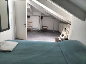 Ein Schlafzimmer mit Bett, Sessel, Schreibtisch und Fenster.