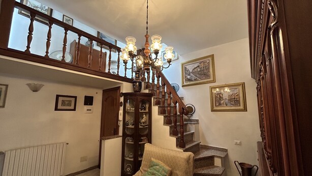 A spacious living room with a high wooden staircase, a chandelier, and a comfortable armchair. - Dora Apartment central location near best beaches (Monterosso al Mare)