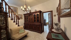 A spacious living room with a wooden staircase, a large wooden cabinet, a sofa, and a decorative ceramic pig. - Dora Apartment central location near best beaches (Monterosso al Mare)