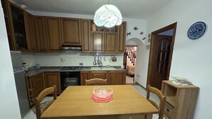 A dining area with a wooden table and chairs, a kitchen in the background, and a decorative plate on the wall. - Dora Apartment central location near best beaches (Monterosso al Mare)