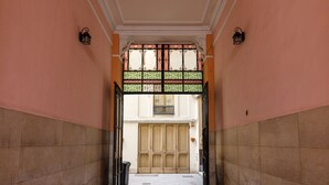 A hallway with a large wooden door at the end, flanked by two black lantern-style wall lights. - Onlyrooms IV - Sea View & Free Parking (Cagliari)