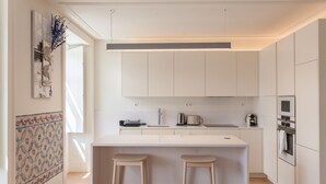 A modern kitchen with white cabinetry, a central island with stools, and a patterned backsplash.