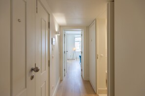 Stroll down this serene hallway, lined with doors leading to spaces and a window offering a glimpse of the outdoors.