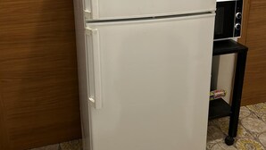 A white Bosch refrigerator in a kitchen with a wooden door and patterned floor tiles. - VENICE NIGHT 25 DOUBLE ROOM  A (Mestre)