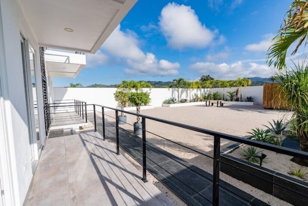 A balcony with a view of a landscaped area, including plants and a clear sky.