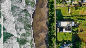 Vista aerea di una proprietà costiera con spiaggia sabbiosa, area verdeggiante e alcuni edifici.