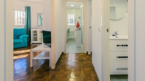 A hallway with a wooden floor, a teal sofa, a white table, and a white cabinet with drawers. - Madrid Rio Perfect location for exploring Madrid! Modern 1-bed flat sleeps 2. (Madrid)