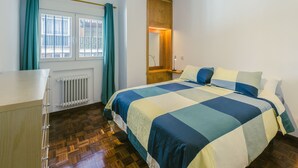 A bedroom with a bed, a dresser, a window with curtains, a radiator, and a wooden wardrobe. - Madrid Rio Perfect location for exploring Madrid! Modern 1-bed flat sleeps 2. (Madrid)