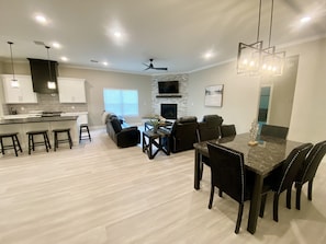 A modern kitchen with white cabinets, a central island, and a dining area with a dark wood table and chairs. - Gorgeous, 3 rm 3.5 bath w/huge patio under home minutes from Kemah water front. (Kemah)