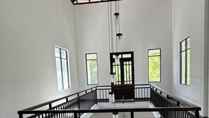 Ein großzügiger Innenraum mit hoher Decke, zahlreichen Fenstern und einer zentralen Treppe.