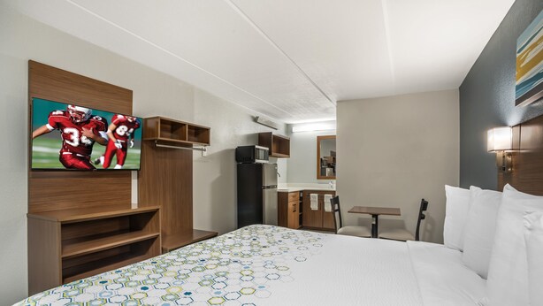 Une chambre d’hôtel avec un grand lit, une télévision, un four à micro-ondes et une petite kitchenette.