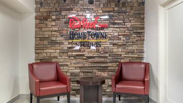 A reception area with a stone wall, two red leather chairs, and a small table.