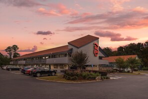 A motel with a parking lot, a building with a sloped roof, and a sign that reads 'Red Roof Inn'. - HomeTowne Studios by Red Roof Greenville (Greenville)