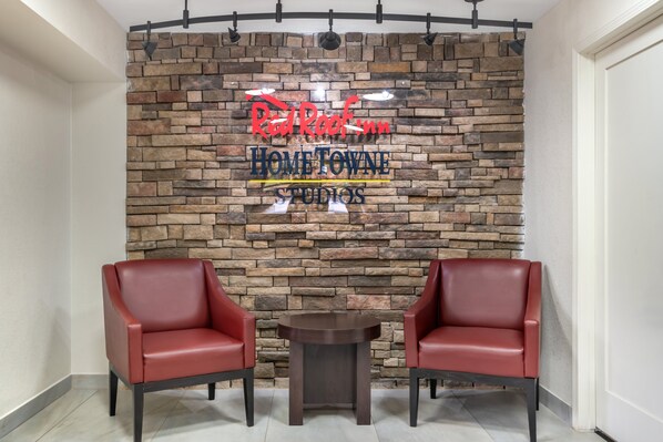 A reception area with a stone wall, two red leather chairs, and a small table.