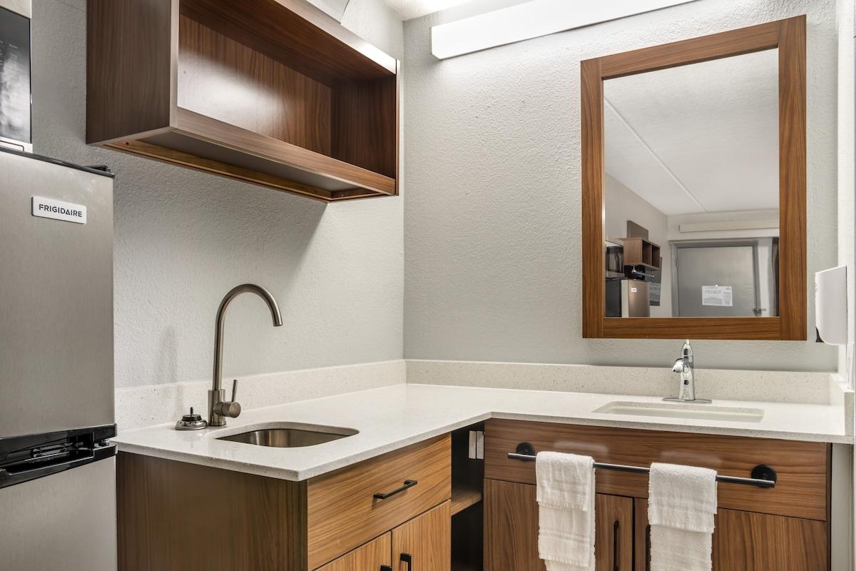 A modern bathroom with a sink, mirror, and wooden cabinets.