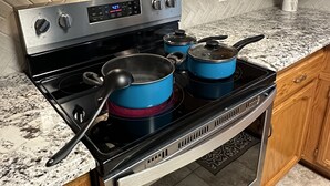 Uma cozinha com fogão de aço inoxidável, micro-ondas acima, armários de madeira e bancada de granito.