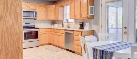 A kitchen with wooden cabinets, a microwave, a stove, a dishwasher, and a dining table with chairs.