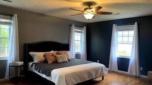 Quarto com cama, ventilador de teto e janelas.