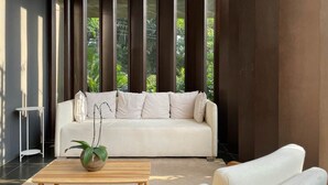A modern living room with a white sofa, a wooden coffee table, and a potted plant. - Onze22 NR (São Paulo)