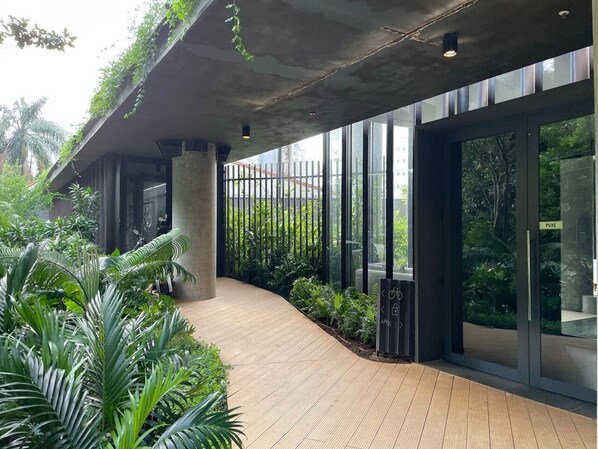 A modern building with a covered walkway, large windows, and lush greenery.