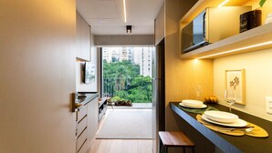 A modern kitchen with a built-in microwave, a wooden countertop, and a view of greenery outside. - Onze22 NR (São Paulo)