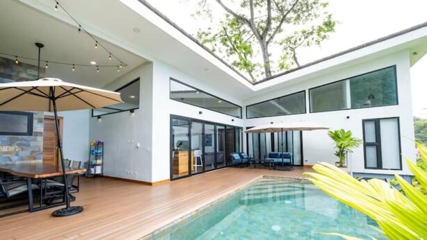 Ein modernes Haus mit Swimmingpool, großen Fenstern und einem Essbereich.