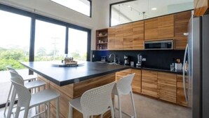 Eine moderne Küche mit einer großen Kochinsel, Holzschränken und weißen Barhocker.