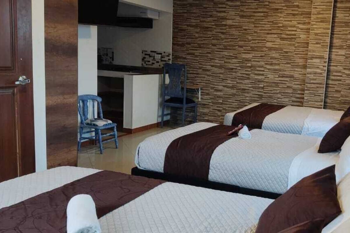 Habitación de hotel con dos camas, pared de madera, escritorio y una silla.