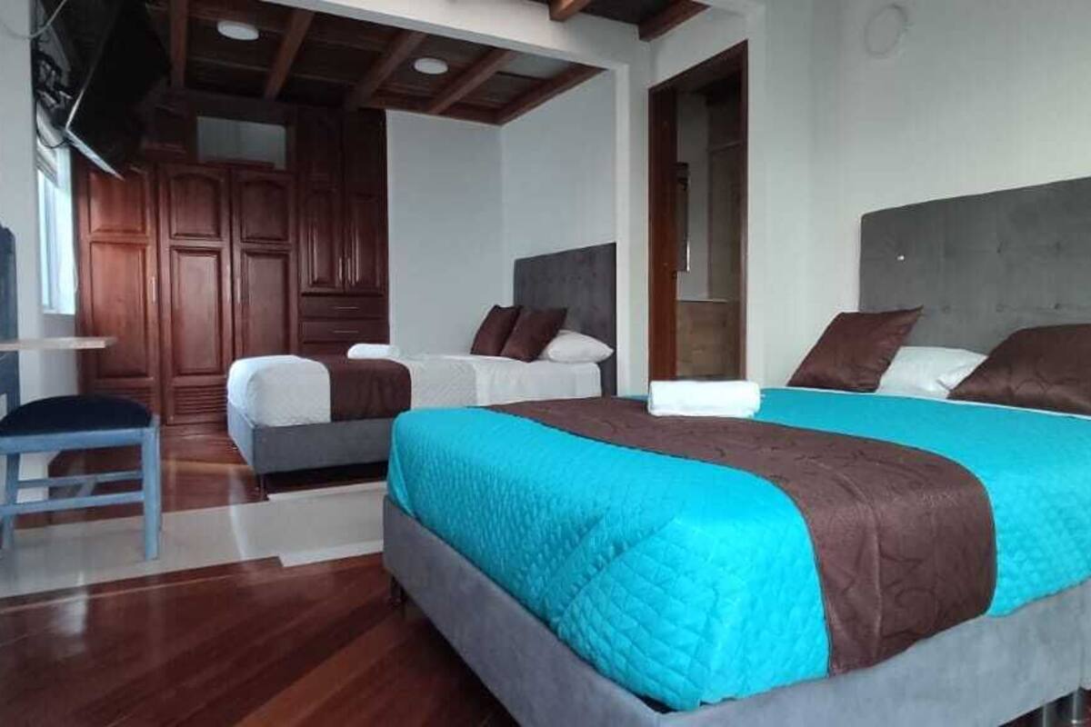 Habitación de hotel con dos camas, piso de madera y diseño moderno.